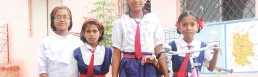 Four smiling girls in school uniforms, representing the importance of girl child education and empowerment.